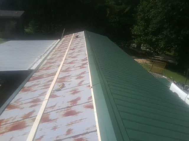 Old rusted panels beside newly installed green metal roofing — Wind Damage Roof Repair by Roofing Brothers in Rhine