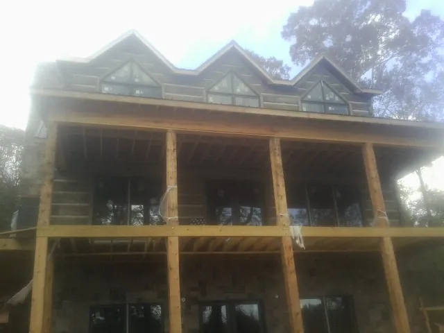 Dormers and porch framing on a large log home under construction — Roof Coating work by our crew in Rhine