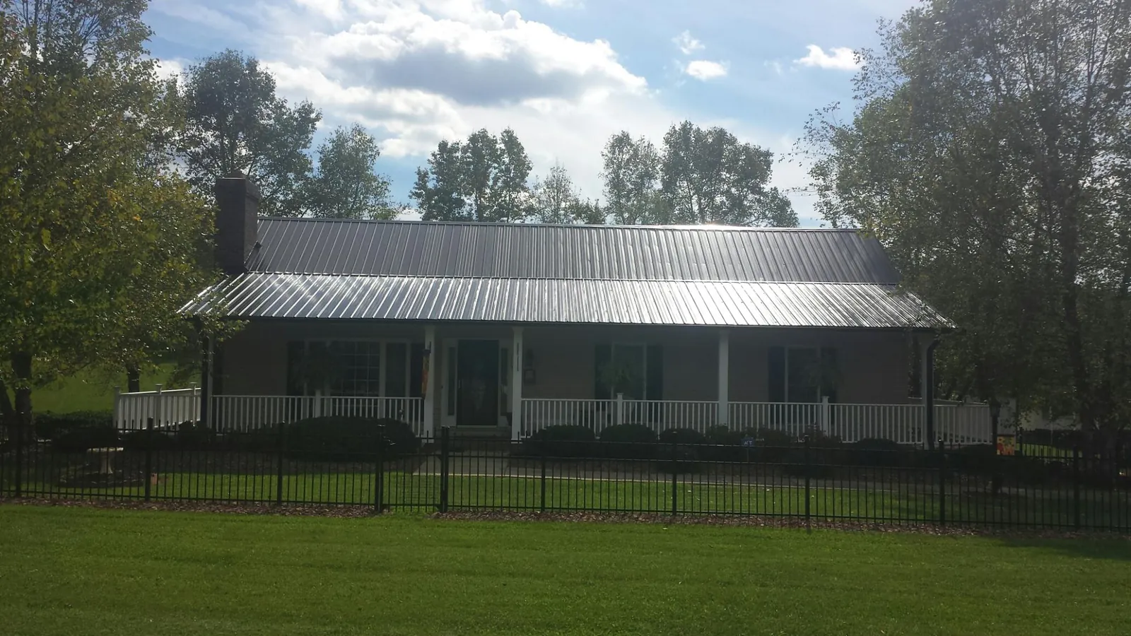 Gray metal roof on a brick ranch with a full width front porch — Gutter Guard Installation work by our crew in Rhine